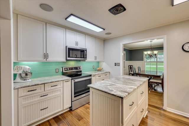 213 Oak Ln, Waynesboro, GA 30830 - kitchen featuring appliances with stainless steel finishes, light wood-style flooring, a chandelier, backsplash, and wainscoting
