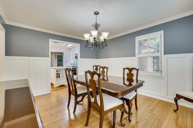 213 Oak Ln, Waynesboro, GA 30830 - dining area with a decorative wall, a wainscoted wall, light wood-style floors, crown molding, and a chandelier