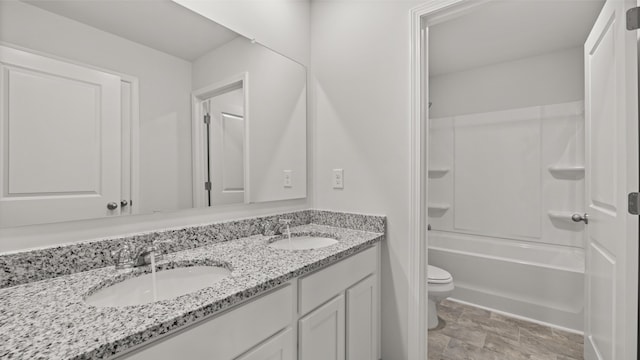 bathroom featuring a sink, toilet, double vanity, and shower / tub combination