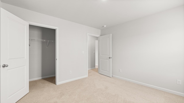 unfurnished bedroom featuring a closet, light colored carpet, and baseboards