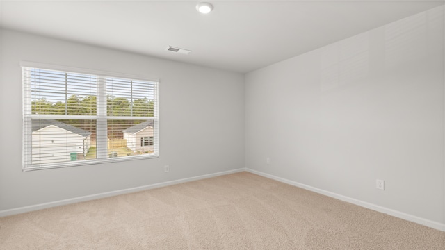 unfurnished room featuring visible vents, light carpet, and baseboards