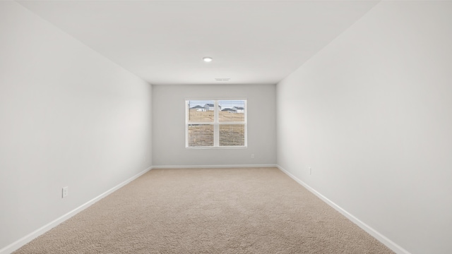 unfurnished room with light colored carpet and baseboards