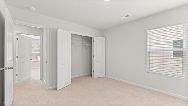 unfurnished bedroom featuring baseboards, light carpet, visible vents, and a closet