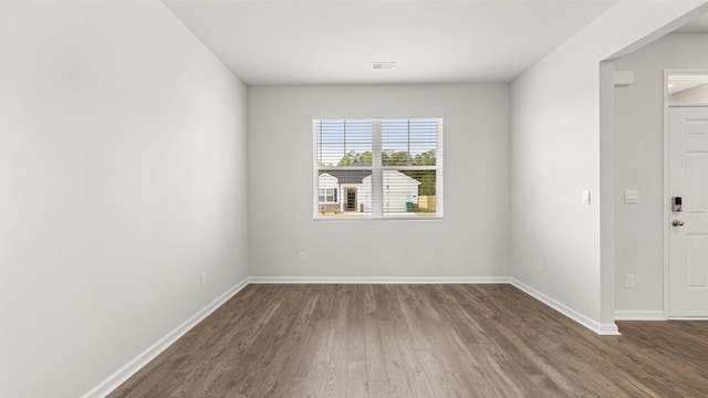 empty room featuring visible vents, baseboards, and wood finished floors