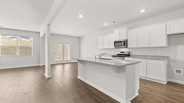 kitchen with dark wood finished floors, white cabinets, appliances with stainless steel finishes, and a sink