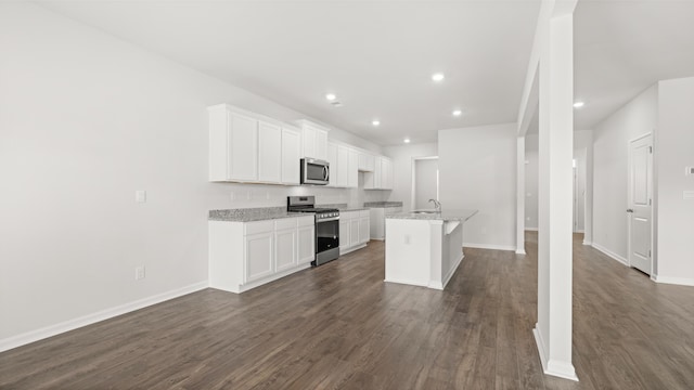 kitchen with an island with sink, appliances with stainless steel finishes, white cabinetry, and dark wood-type flooring