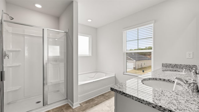 full bath featuring a sink, double vanity, a bath, and a shower stall