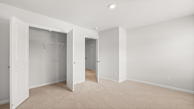 unfurnished bedroom with light carpet, baseboards, and a closet