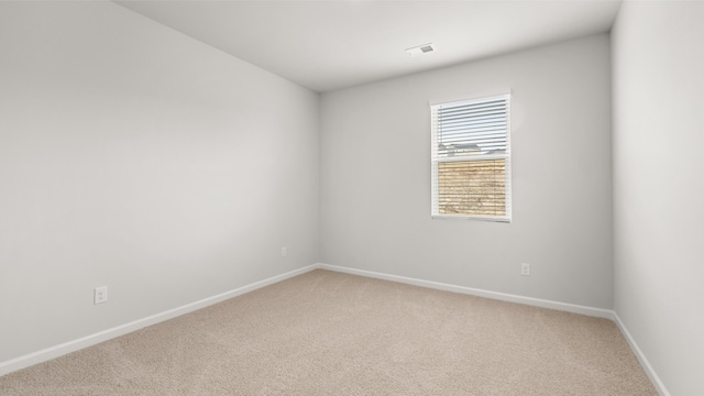 spare room with baseboards, light carpet, and visible vents