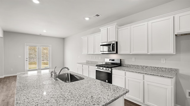 kitchen featuring light stone countertops, recessed lighting, white cabinets, stainless steel appliances, and a sink