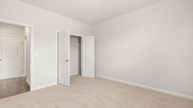 unfurnished bedroom with baseboards, carpet floors, and a closet