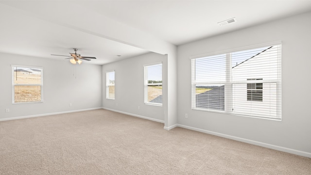 spare room with a ceiling fan, light colored carpet, visible vents, and baseboards