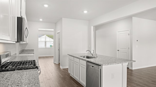 kitchen featuring light stone countertops, a sink, dark wood-type flooring, appliances with stainless steel finishes, and white cabinetry