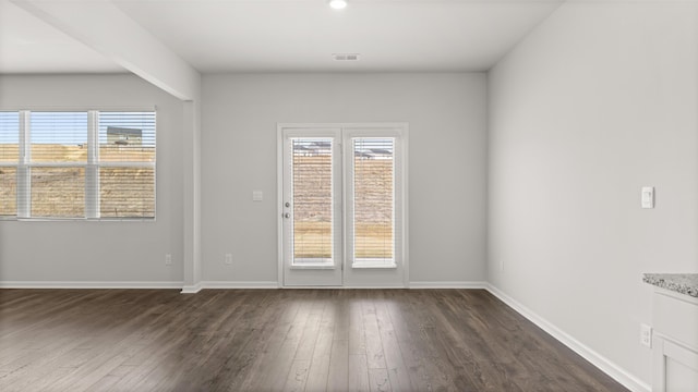 spare room with visible vents, baseboards, and dark wood-style flooring