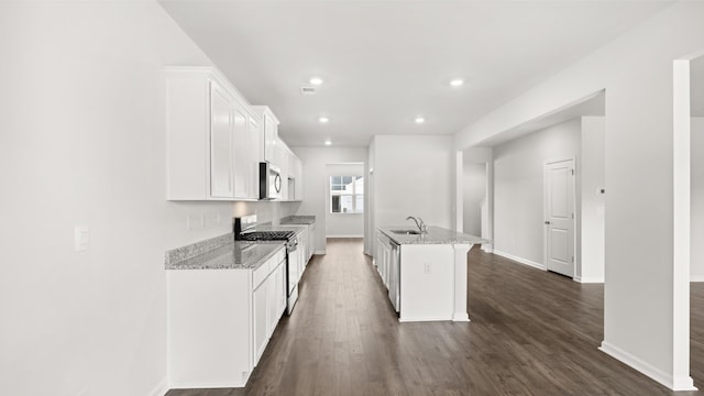 kitchen with light stone counters, dark wood-style flooring, a sink, appliances with stainless steel finishes, and white cabinetry