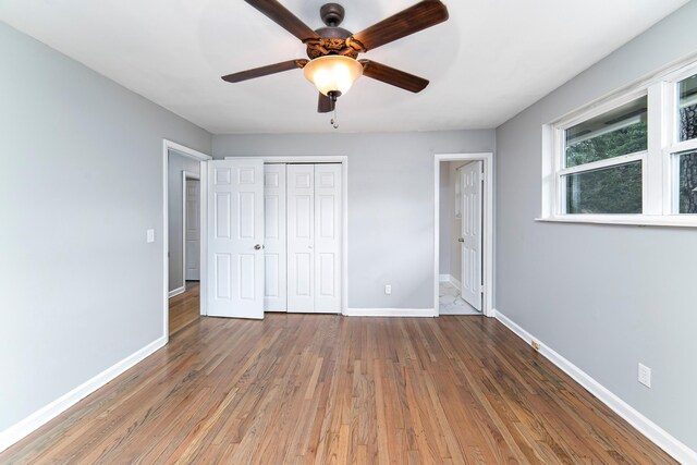 unfurnished bedroom with a closet, dark hardwood / wood-style floors, and ceiling fan