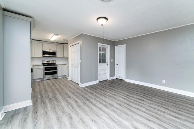 kitchen with light wood-type flooring, ornamental molding, and stainless steel appliances