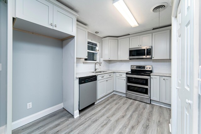 kitchen featuring sink, light stone countertops, stainless steel appliances, and hanging light fixtures