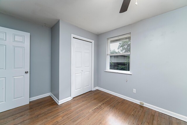 unfurnished bedroom featuring ceiling fan, a closet, and hardwood / wood-style flooring