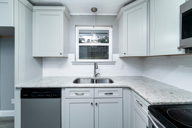 kitchen with light stone countertops, sink, decorative light fixtures, white cabinets, and appliances with stainless steel finishes