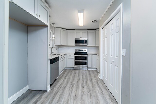 kitchen with hanging light fixtures, light hardwood / wood-style floors, sink, and appliances with stainless steel finishes