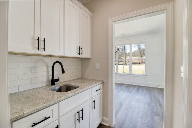 1086 Birdie Pl, Graniteville, SC 29829 - kitchen featuring wood finished floors, light stone counters, decorative backsplash, a sink, and white cabinetry