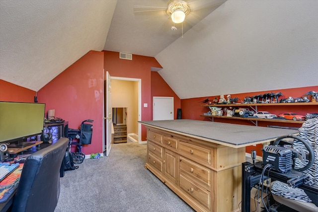 carpeted office featuring a textured ceiling, vaulted ceiling, and ceiling fan