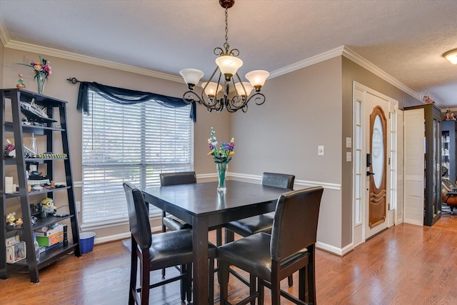 dining area featuring ornamental molding, a textured ceiling, a notable chandelier, and hardwood / wood-style floors