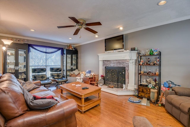 living room with a fireplace, hardwood / wood-style floors, ceiling fan, and crown molding