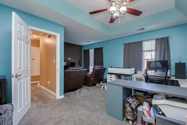 carpeted office featuring ceiling fan, a raised ceiling, and a textured ceiling