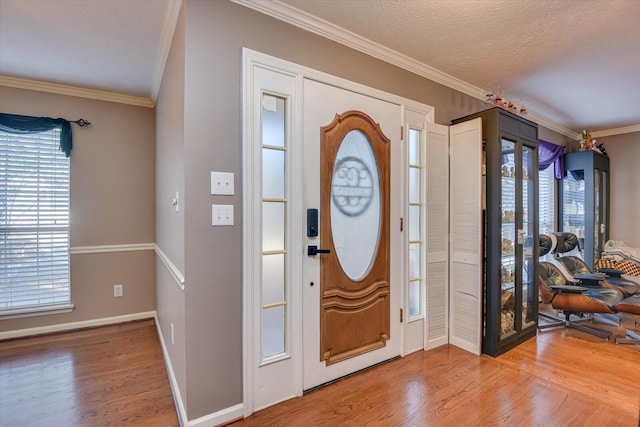 entryway with wood-type flooring, a textured ceiling, and crown molding