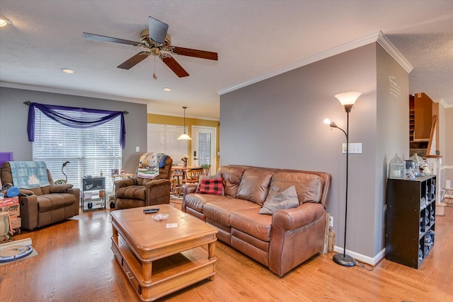 living room featuring crown molding, ceiling fan, a textured ceiling, and light wood-type flooring