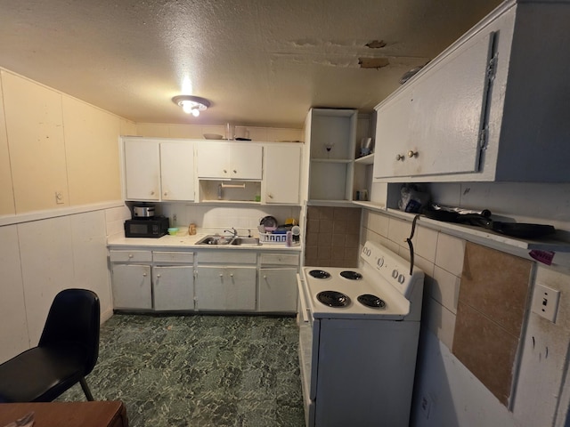 406 E Espinosa St, Augusta, GA 30901 - kitchen with white range with electric cooktop, black microwave, white cabinetry, wainscoting, and light countertops