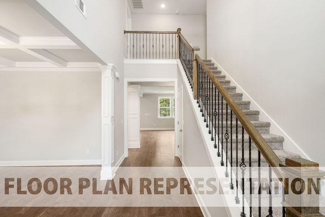 stairs featuring ornate columns, beamed ceiling, coffered ceiling, and hardwood / wood-style flooring