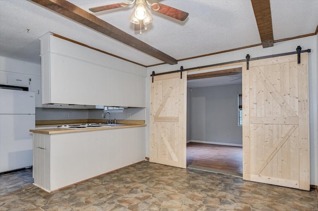 kitchen with beam ceiling, a barn door, a textured ceiling, and white refrigerator