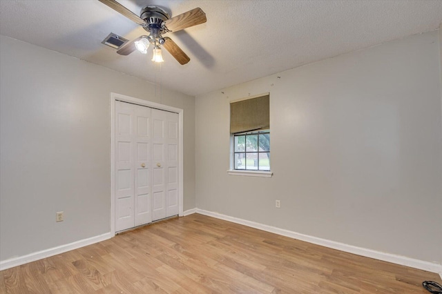 unfurnished bedroom with ceiling fan, a closet, a textured ceiling, and light hardwood / wood-style flooring