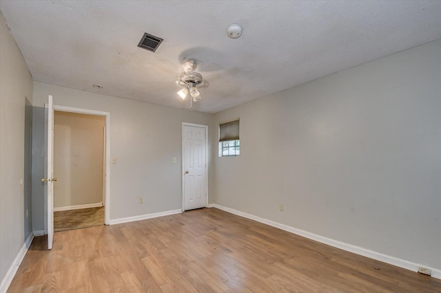 empty room with ceiling fan, light hardwood / wood-style floors, and a textured ceiling