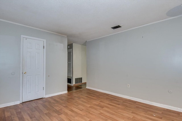 spare room with a textured ceiling, light hardwood / wood-style flooring, and ornamental molding