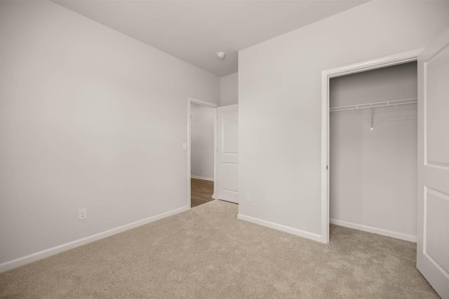 unfurnished bedroom featuring a closet and light colored carpet