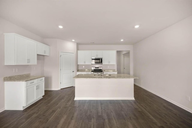 kitchen featuring stainless steel appliances, white cabinetry, and an island with sink