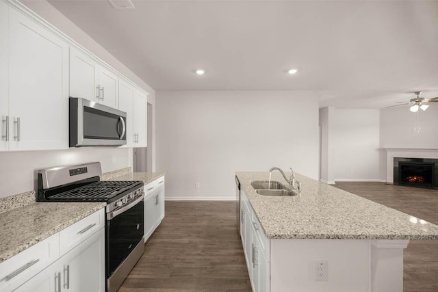 kitchen with sink, light stone counters, an island with sink, white cabinets, and appliances with stainless steel finishes