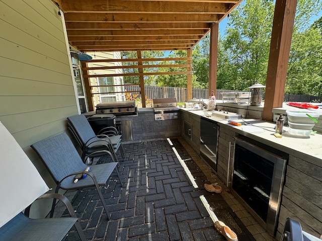 view of patio with exterior kitchen, a grill, wine cooler, and fence