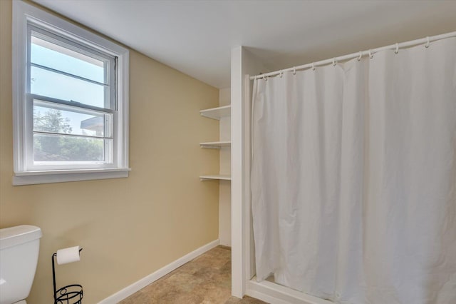 bathroom featuring toilet, curtained shower, and a healthy amount of sunlight