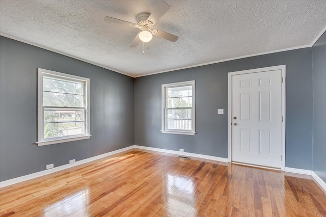 empty room featuring hardwood / wood-style flooring, ceiling fan, ornamental molding, and a textured ceiling