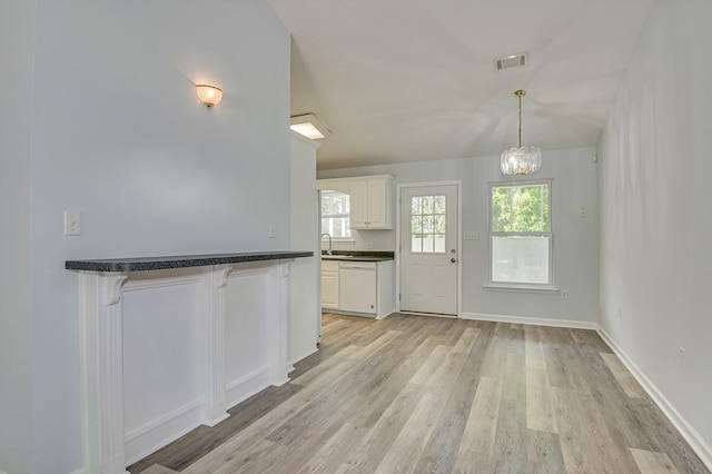 2273 Pund Ave, Augusta, GA 30904 - kitchen featuring dark countertops, a breakfast bar area, light wood-style floors, a chandelier, and white cabinets