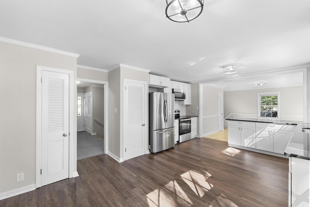 kitchen featuring kitchen peninsula, appliances with stainless steel finishes, ornamental molding, dark wood-type flooring, and white cabinetry