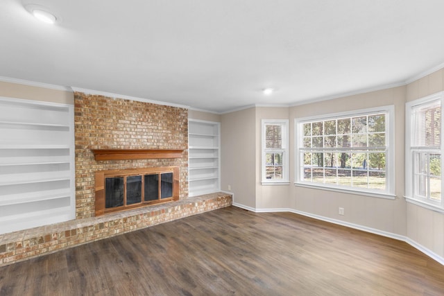 unfurnished living room featuring built in features, dark wood-type flooring, a brick fireplace, and crown molding