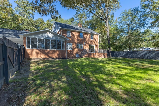 rear view of house with a yard, a deck, and a sunroom