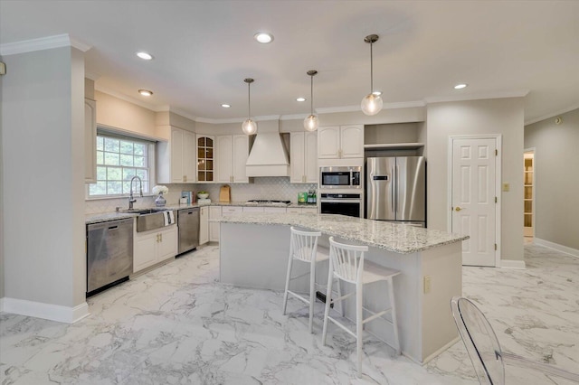 kitchen with a center island, premium range hood, light stone countertops, appliances with stainless steel finishes, and white cabinetry