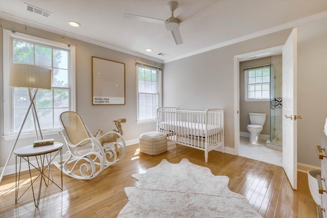 bedroom with multiple windows, ceiling fan, light hardwood / wood-style flooring, and a crib